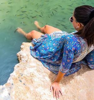 ženska, ki sedi na skali ob vodi