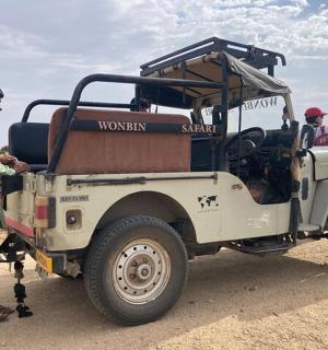 一名男子站在沙漠中的一辆吉普车旁