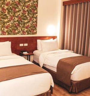 一间有两张床的酒店房间，墙上挂着一幅画