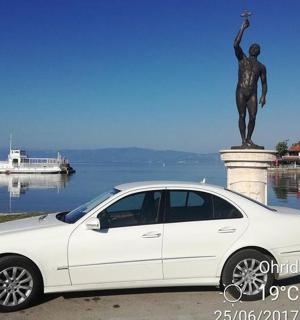 a white car parked in front of a statue