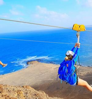 two people on a zip line over the ocean