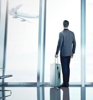 a man standing in an airport with a suitcase