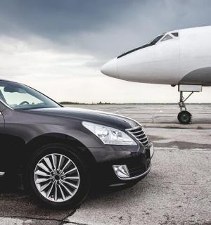 Černé auto je zaparkované vedle letadla
