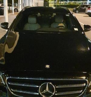 acedes benz car parked in a parking lot with two people