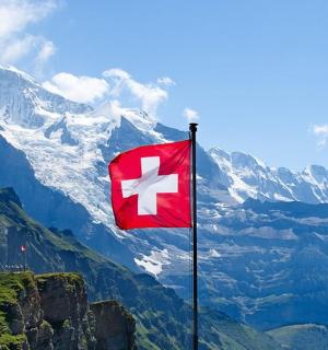 červená vlajka s bílým křížem na vrcholu hory