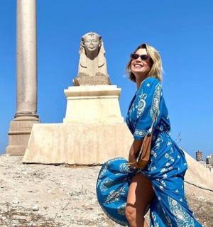 一位身穿蓝色连衣裙的女子坐在纪念碑前