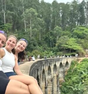 三个女孩坐在桥边的墙上