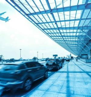 Letadlo přelétá nad auty zaparkovanými na letišti