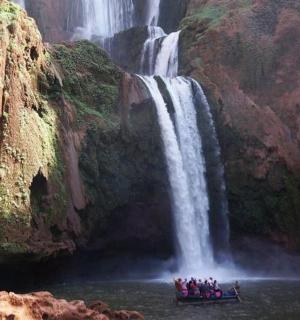 a group of people in a boat in front of a waterfall