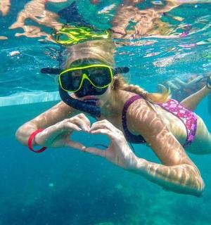 a man and a woman making a heart shape in the water