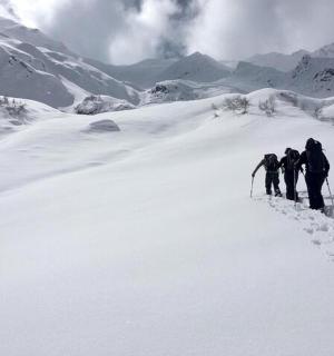 一组三人徒步攀登白雪皑皑的山峰