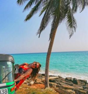 一名女子站在海滩上的一辆卡车旁边