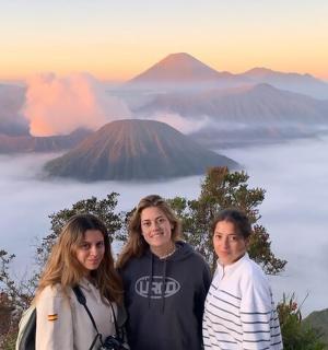 a group of three people standing in front of a mountain