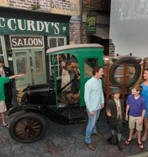 a group of people standing in front of an old car