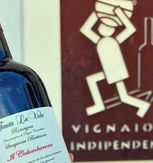 一个人拿着一瓶酒站在标志旁边