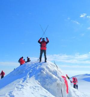 seorang lelaki berdiri di atas gunung yang dilitupi salji