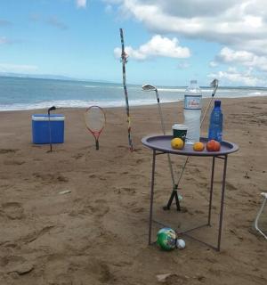 沙滩上的一张桌子和几把椅子，还有球拍