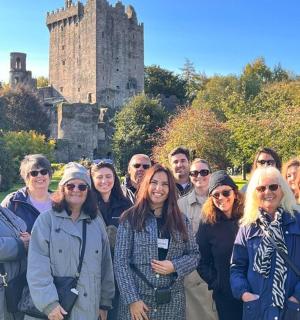 skupina lidí stojící před hradem