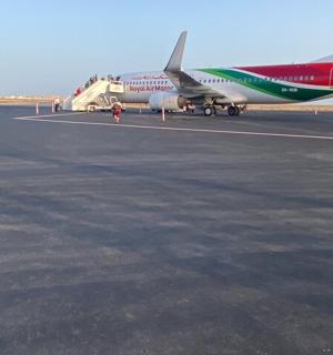 a red and green airplane sitting on an airport runway