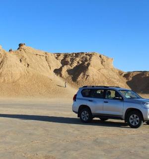 一辆白色卡车停在沙漠中，山