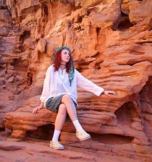 一位女士坐在峡谷的一块岩石上