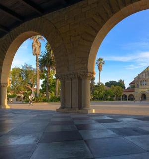 an arcade with a building in the background with palm trees