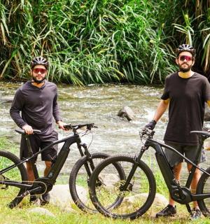 两名男子站在小溪前的自行车旁