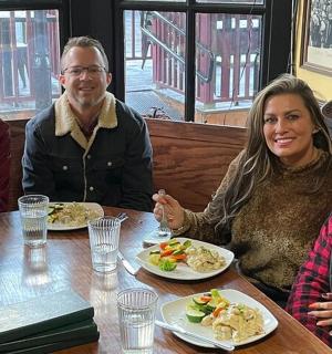 a group of people sitting at a table with plates of food
