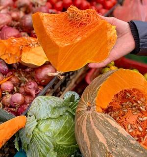 a person holding up a pumpkin in a market