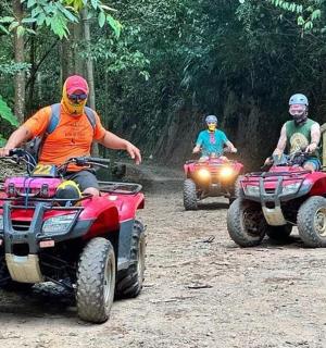 three people riding atvs on a dirt road