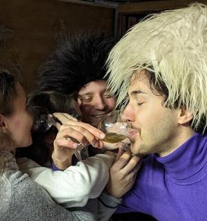 muž s parukou pije sklenici vína