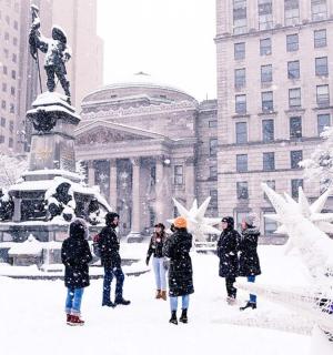 a group of people walking in the snow in front of a statue