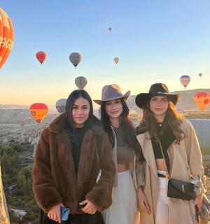 three women standing in front of a view of hot air balloons
