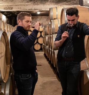 两个男人站在摆满酒桶的酒窖里