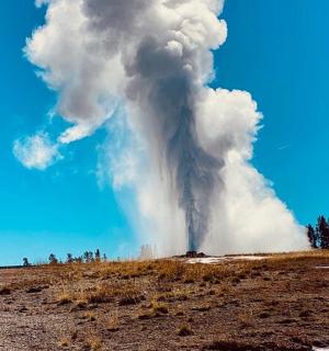 a plume of steam from a volcano in a field