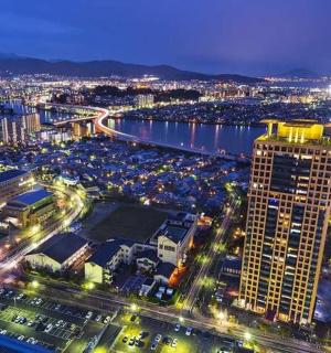 eine Stadt bei Nacht mit einem Fluss und einem hohen Gebäude