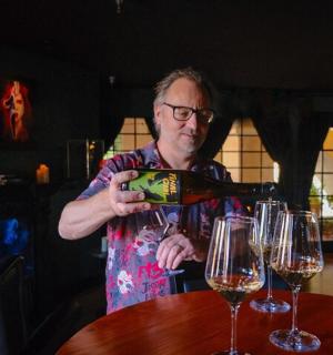 一位男士在餐桌上往酒杯里倒酒