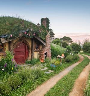 a stone house with a red door and a dirt road