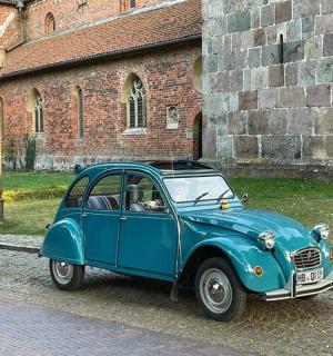 an old blue car parked in front of a building