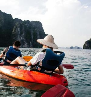 two people in kayaks on the water with mountains in the background