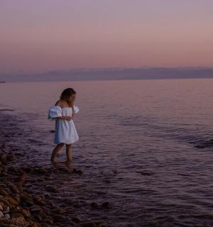 一个穿着白色连衣裙的女孩站在海滩上