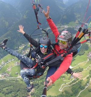 două persoane atârnă de o parașută