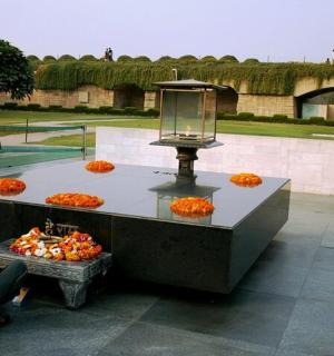 一位男士坐在摆着橘子的柜台旁的长凳上