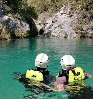 two people wearing helmets in the water in a river