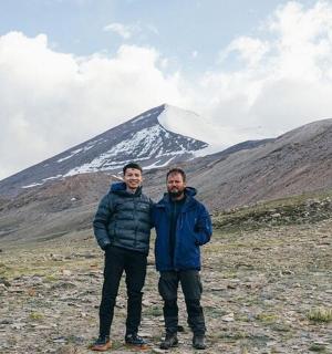 two men standing in front of a mountain