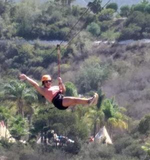 a man flying through the air on a zip line
