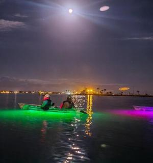 skupina lidí v lodích na vodě v noci