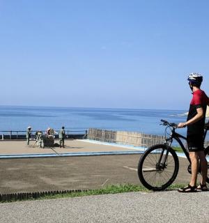 a man standing next to a bike on the beach