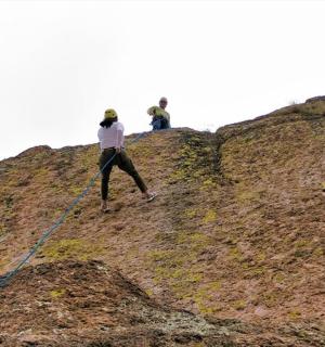two people standing on top of a hill with a rope