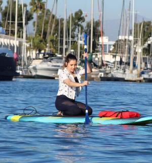 a young boy is sitting on a paddle board in the water